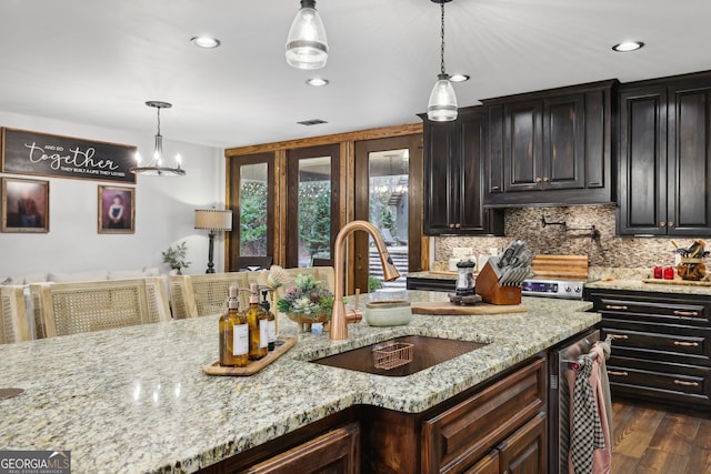 kitchen featuring sink, hanging light fixtures, dark hardwood / wood-style floors, dark brown cabinets, and light stone counters