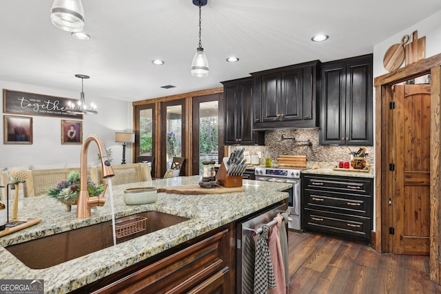 kitchen featuring sink, hanging light fixtures, stainless steel appliances, light stone counters, and dark hardwood / wood-style flooring