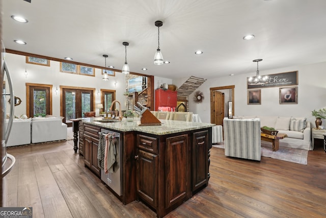 kitchen with dark hardwood / wood-style flooring, sink, an island with sink, and decorative light fixtures