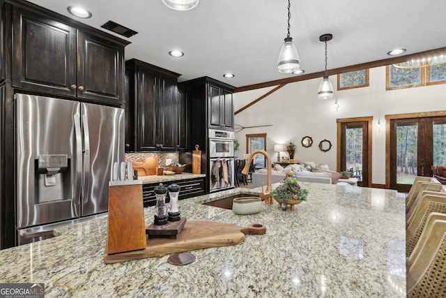 kitchen with sink, decorative backsplash, light stone countertops, decorative light fixtures, and stainless steel appliances