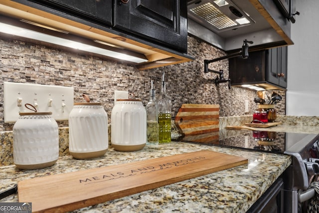 kitchen with stainless steel range, decorative backsplash, light stone counters, and exhaust hood