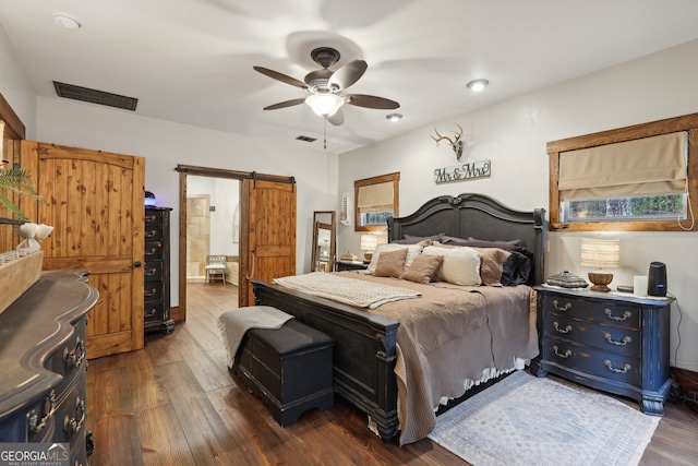 bedroom with a barn door, ceiling fan, and dark wood-type flooring