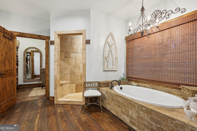 bathroom with hardwood / wood-style flooring, an inviting chandelier, and independent shower and bath