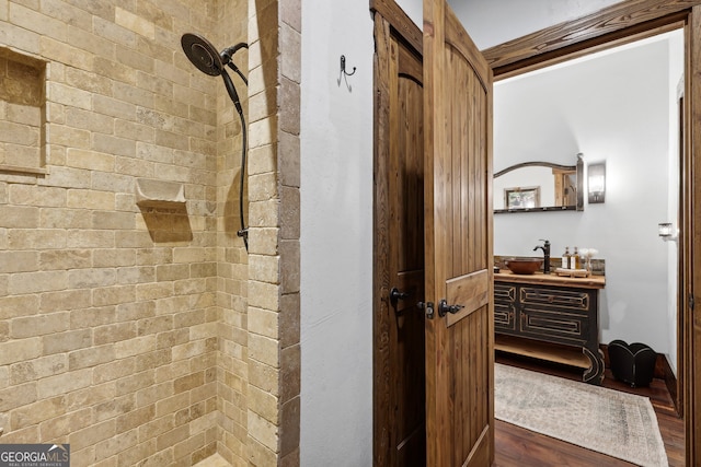 bathroom featuring vanity, wood-type flooring, and tiled shower