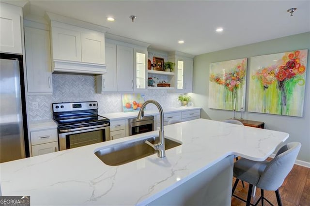 kitchen with light stone counters, white cabinets, appliances with stainless steel finishes, and sink