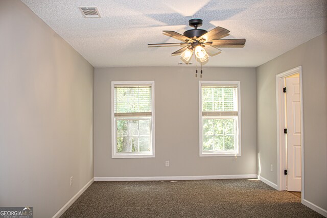 carpeted empty room with ceiling fan, a textured ceiling, and plenty of natural light