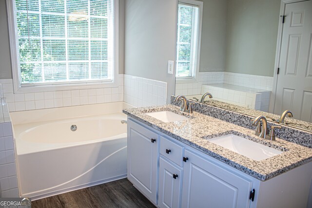 bathroom featuring tile walls, wood-type flooring, a bath, and vanity