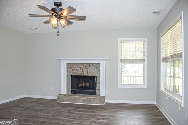 unfurnished living room with a textured ceiling, a fireplace, dark hardwood / wood-style floors, and ceiling fan