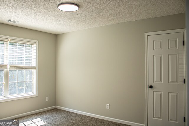 carpeted spare room with a textured ceiling