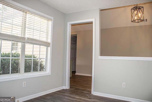 spare room with a textured ceiling and dark hardwood / wood-style floors