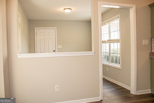 hall featuring a textured ceiling and dark wood-type flooring