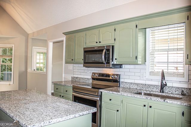 kitchen with lofted ceiling, stainless steel appliances, green cabinets, and a wealth of natural light