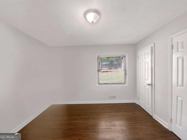 interior space with a textured ceiling and dark hardwood / wood-style flooring