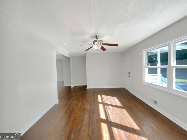 unfurnished room featuring ceiling fan, dark wood-type flooring, and a textured ceiling