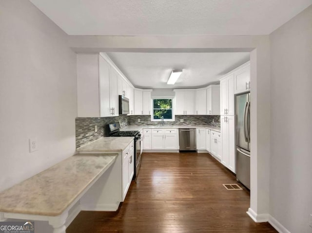 kitchen with sink, tasteful backsplash, white cabinetry, appliances with stainless steel finishes, and dark hardwood / wood-style floors