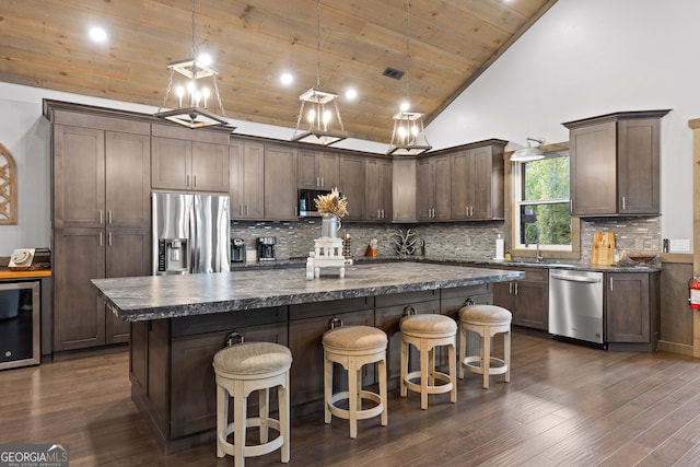 kitchen featuring hanging light fixtures, wood ceiling, dark wood-type flooring, a kitchen island, and stainless steel appliances