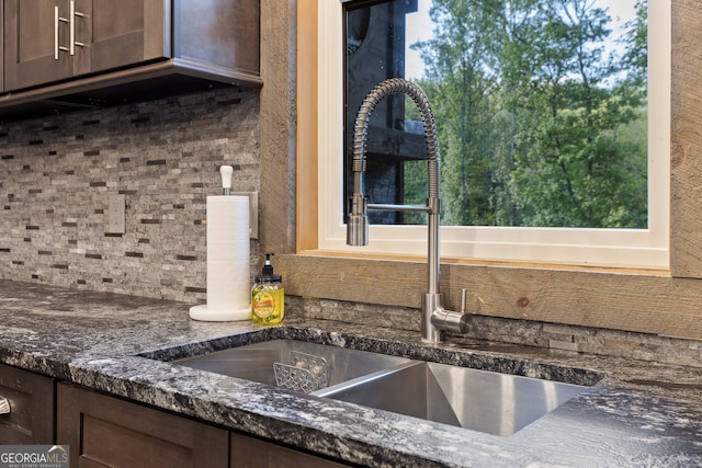 interior details featuring dark brown cabinets, dark stone countertops, sink, and tasteful backsplash