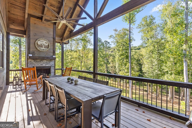 wooden terrace with ceiling fan and an outdoor stone fireplace