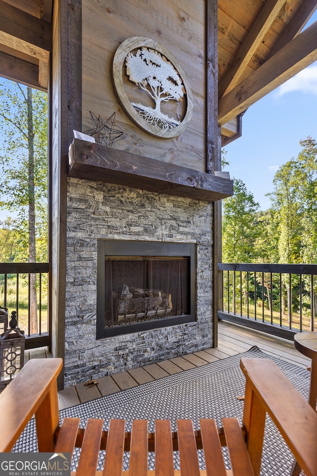 exterior details featuring wood walls, an outdoor stone fireplace, and beamed ceiling