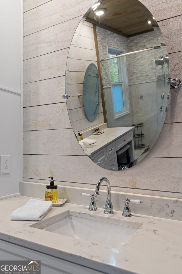 bathroom featuring wooden walls, vanity, and an enclosed shower