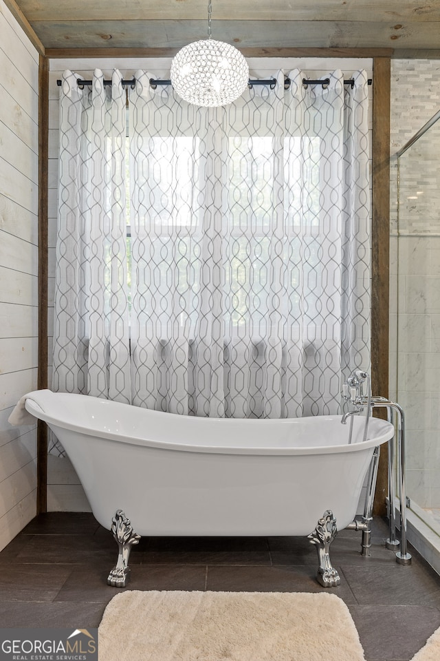 bathroom featuring a tub to relax in and wood walls