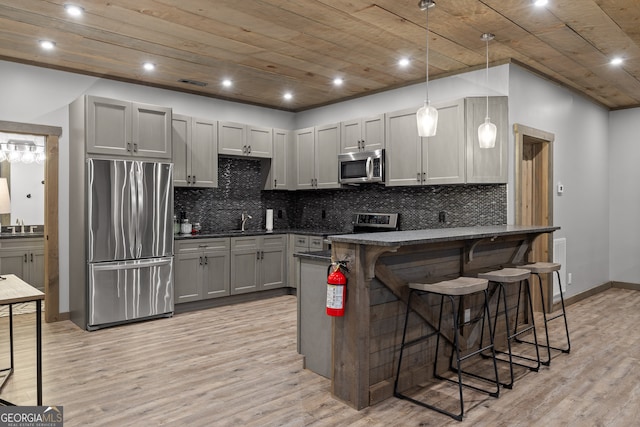 kitchen featuring decorative light fixtures, gray cabinets, appliances with stainless steel finishes, and light hardwood / wood-style floors