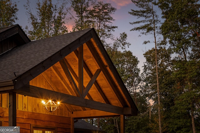 exterior details featuring an inviting chandelier, wood walls, and beamed ceiling