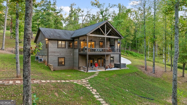 rear view of property featuring a lawn, a balcony, central AC, and a patio area