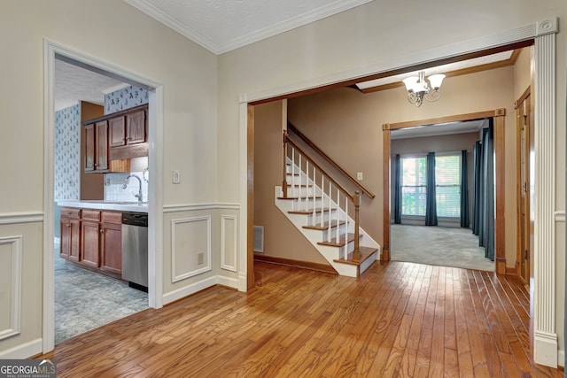 entryway with light hardwood / wood-style flooring, a notable chandelier, sink, and crown molding