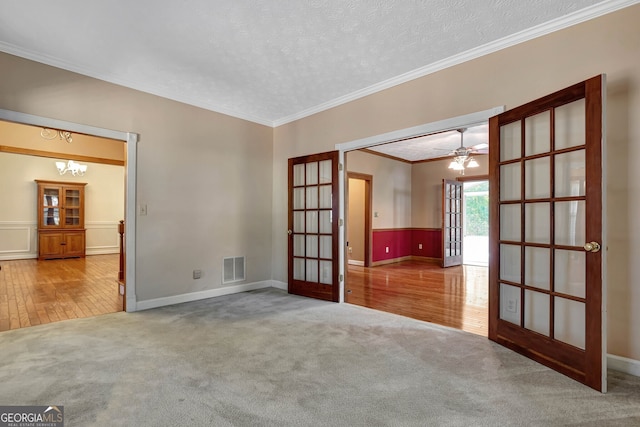 empty room featuring wood-type flooring, a textured ceiling, ceiling fan with notable chandelier, and crown molding