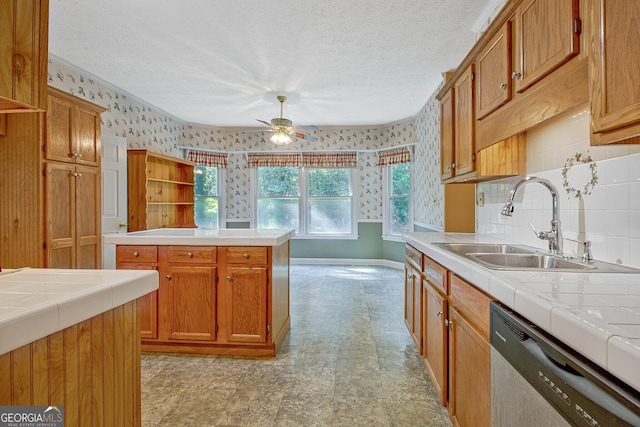 kitchen with ceiling fan, tile countertops, sink, and stainless steel dishwasher