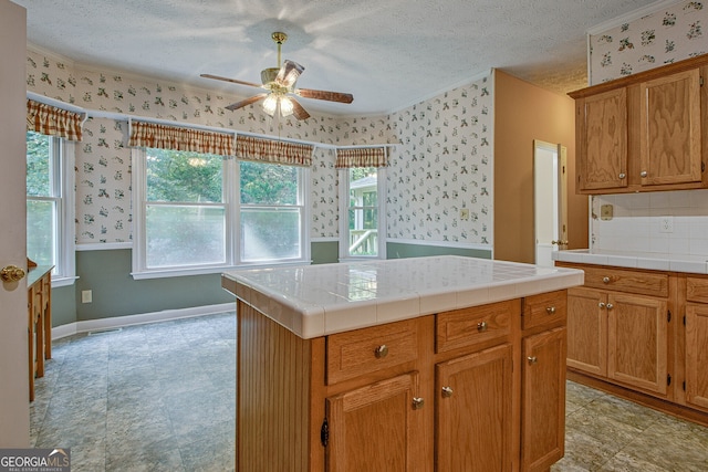 kitchen featuring a center island, ceiling fan, tile counters, and a textured ceiling