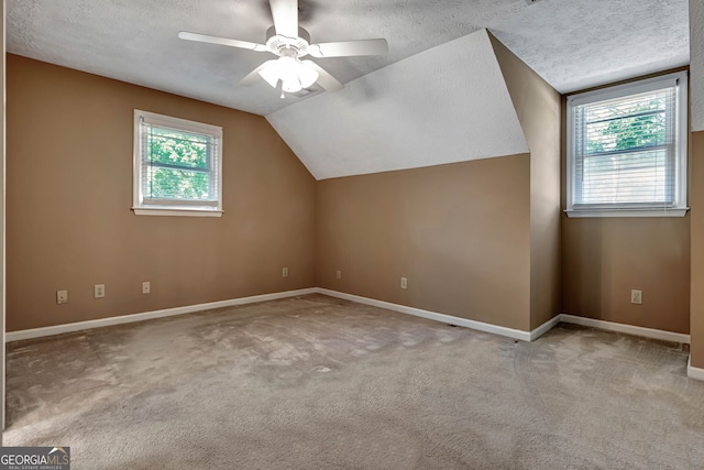 additional living space with ceiling fan, a textured ceiling, vaulted ceiling, and a wealth of natural light