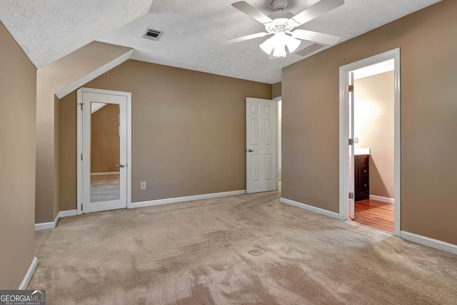 unfurnished bedroom featuring ceiling fan, a textured ceiling, light carpet, and vaulted ceiling