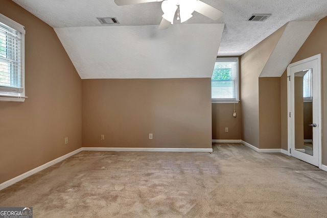 bonus room featuring vaulted ceiling, ceiling fan, light colored carpet, and a textured ceiling