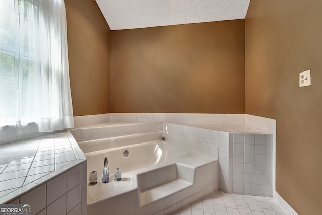 bathroom featuring tile patterned flooring, a textured ceiling, a healthy amount of sunlight, and a bathtub