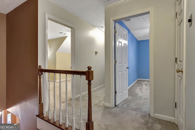 hallway with light carpet and a textured ceiling