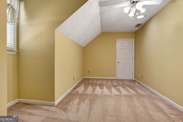 additional living space featuring light carpet, lofted ceiling, a textured ceiling, and ceiling fan