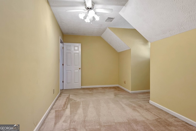 bonus room featuring a textured ceiling, lofted ceiling, light carpet, and ceiling fan