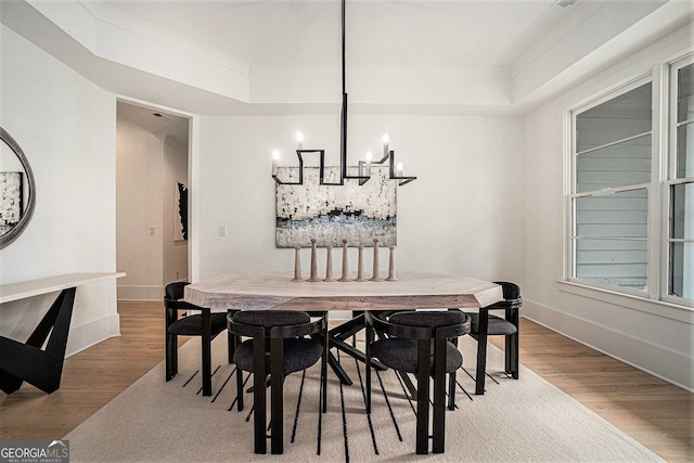 dining area with a chandelier, hardwood / wood-style flooring, and a tray ceiling