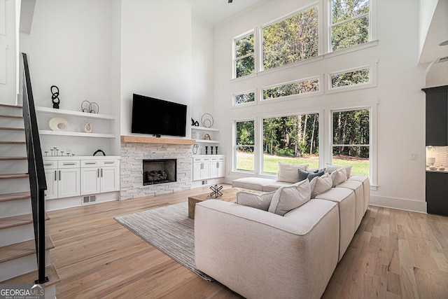 living room featuring a towering ceiling, plenty of natural light, and light hardwood / wood-style floors