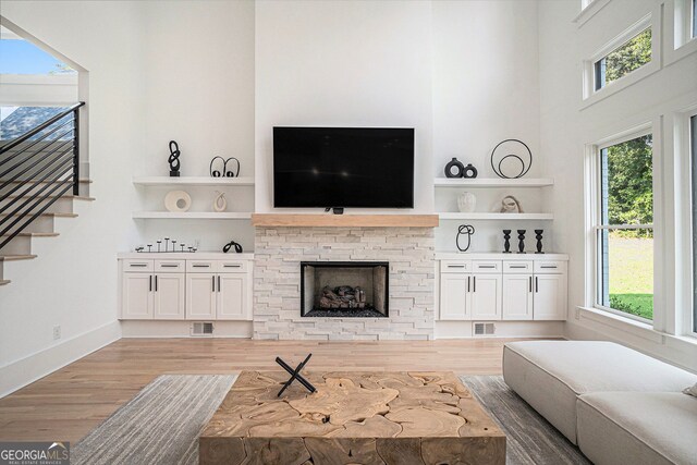 living room with a fireplace, plenty of natural light, a high ceiling, and wood-type flooring