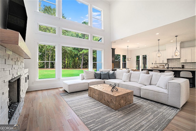 living room with a towering ceiling, plenty of natural light, and light hardwood / wood-style floors