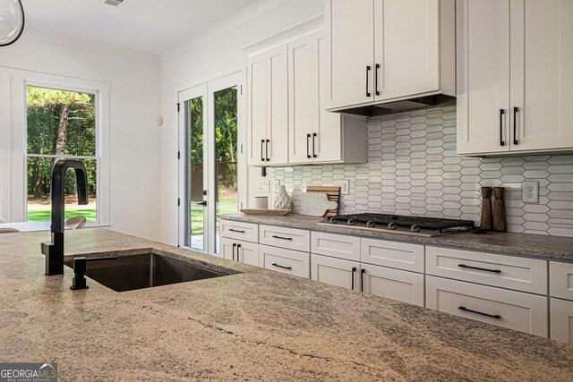 kitchen featuring light stone countertops, sink, decorative backsplash, and white cabinetry