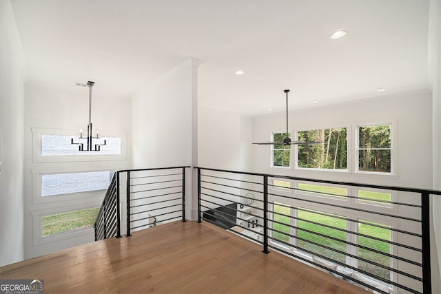 hall featuring ornamental molding, hardwood / wood-style floors, and an inviting chandelier