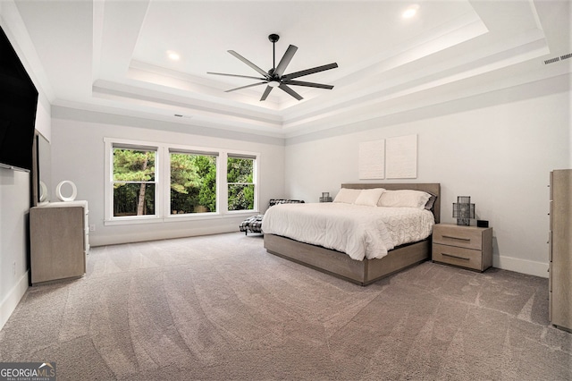 bedroom featuring a raised ceiling, light carpet, crown molding, and ceiling fan