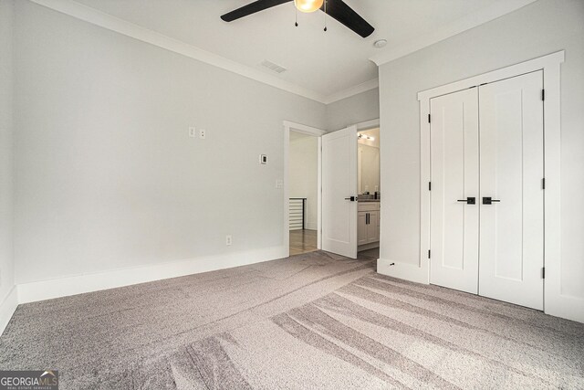 unfurnished bedroom with a closet, crown molding, carpet, and ceiling fan