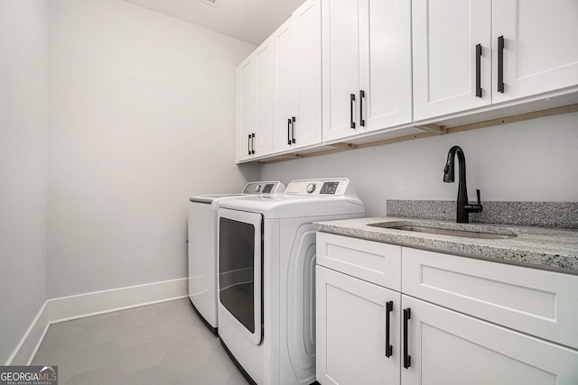 laundry area featuring light tile patterned flooring, washing machine and clothes dryer, cabinets, and sink