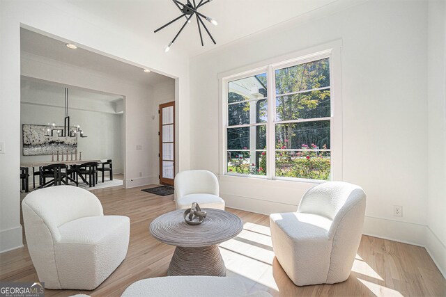 sitting room with a notable chandelier, light wood-type flooring, and plenty of natural light