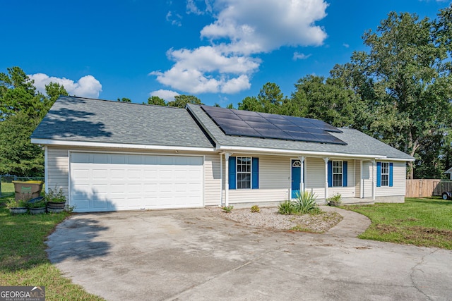 view of front of house featuring a garage, solar panels, and a front lawn